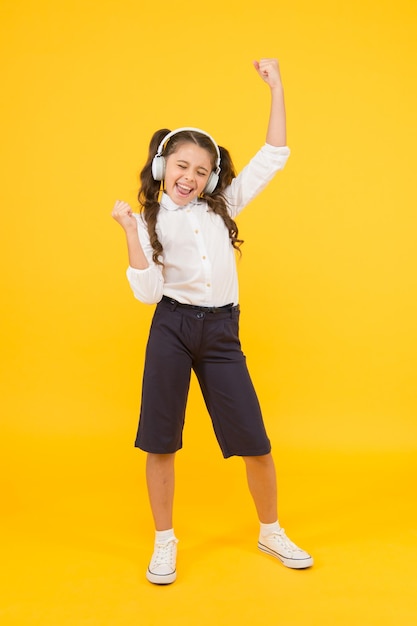 Escola online Lição de audição Criança gosta de som de música Escola de áudio Educação em casa Fones de ouvido de menina pequena Criança feliz ouvindo música Cantar música Livro de áudio Educação e conceito divertido