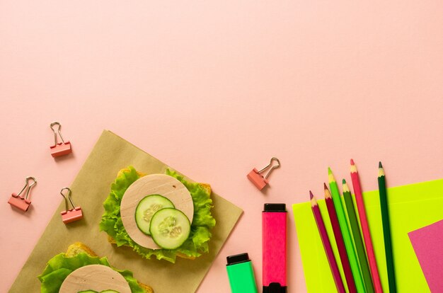 Foto escola plana leigos com sanduíches de papelaria e salsicha em um fundo rosa