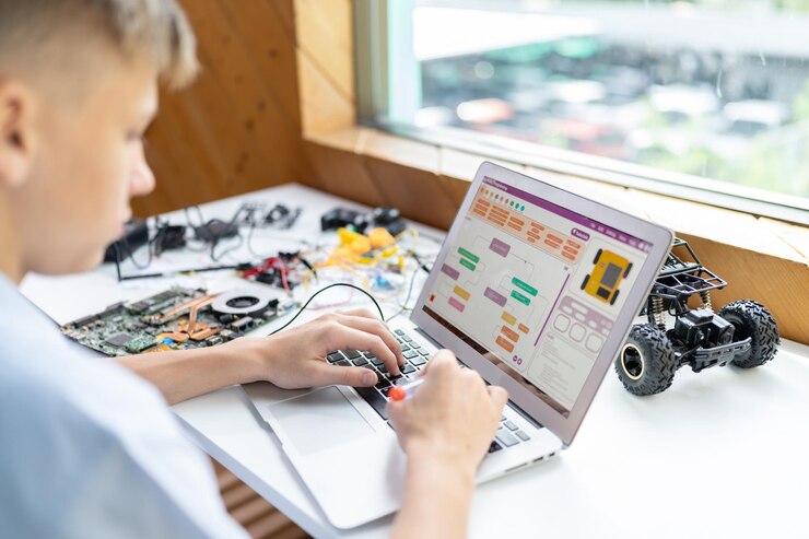 Foto un escolar con camisa azul usa una computadora portátil para codificar un coche robótico en la clase de stem edificación