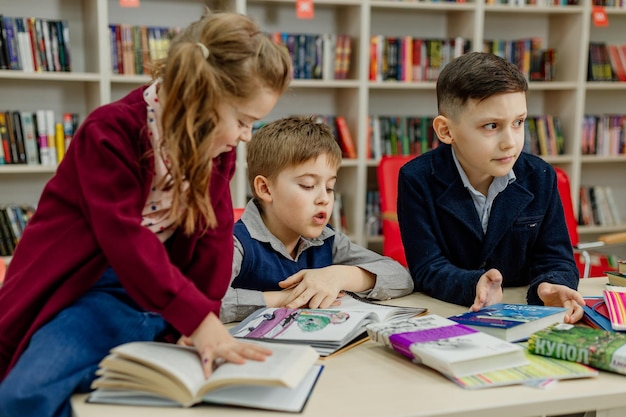 Escolares en la biblioteca leyendo libros, haciendo deberes, preparándose para las lecciones