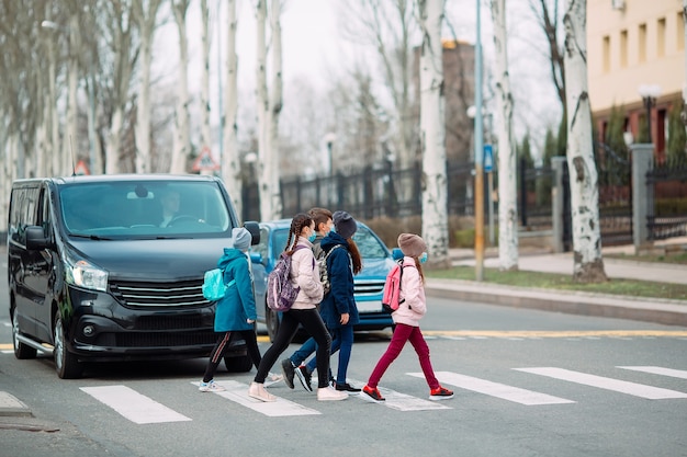 Los escolares cruzan la calle con máscaras médicas.