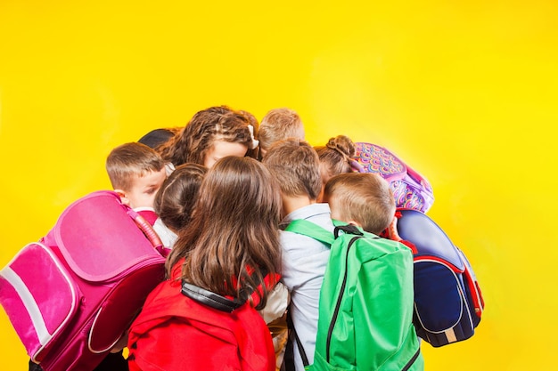 Los escolares están juntando las manos en el fondo amarillo.