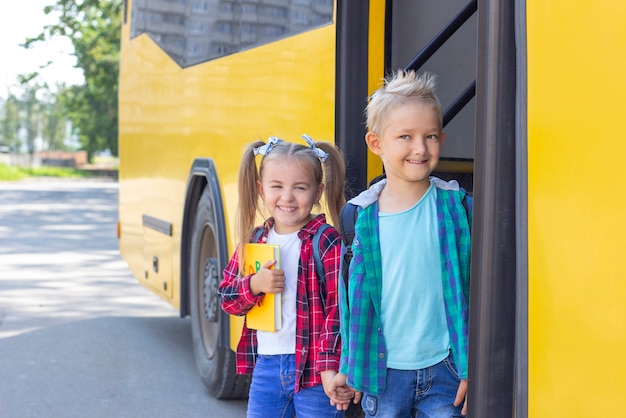 Los escolares felices con mochilas bajan del autobús escolar.