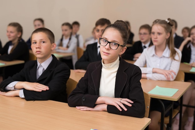 Los escolares felices se sientan en un escritorio en el aula