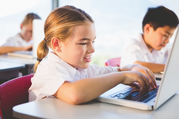 Escolares usando una computadora portátil en el aula