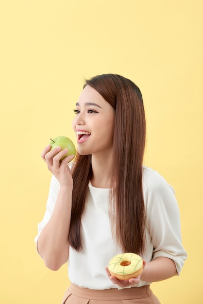 Escolha a escolha certa para uma boa saúde. As mulheres estão escolhendo entre donut e maçã verde isolada em vez de amarela.