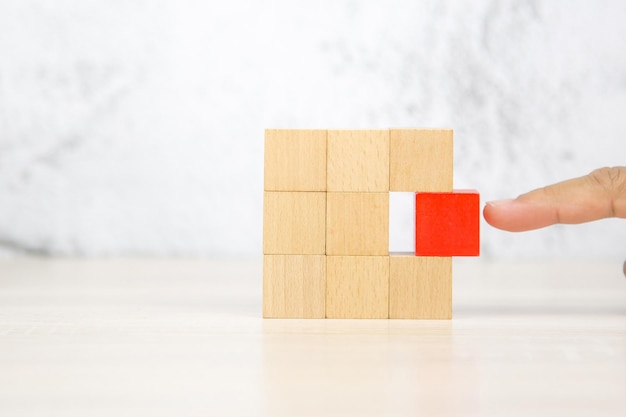 Escolha à mão blocos de brinquedo de madeira de cubo quadrado empilhados na mesa com fundo branco de parede para atividades infantis