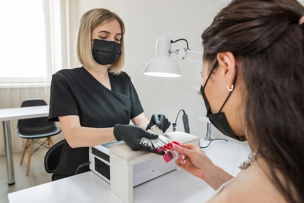 Escolha da cor das unhas uma jovem escolhe a cor das unhas em um salão de beleza beleza e saúde das unhas manicure e cliente em um salão de beleza