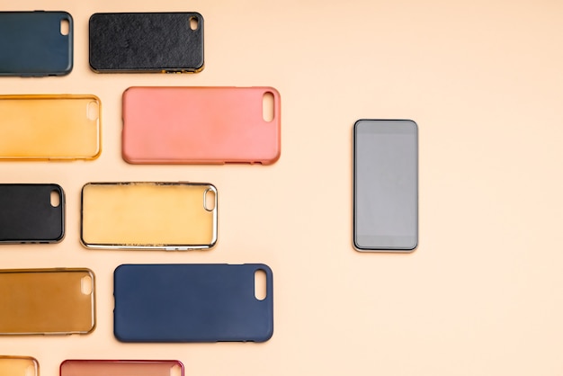 Escolha de capas traseiras de plástico multicoloridas para telefones celulares em fundo neutro com um smartphone na lateral