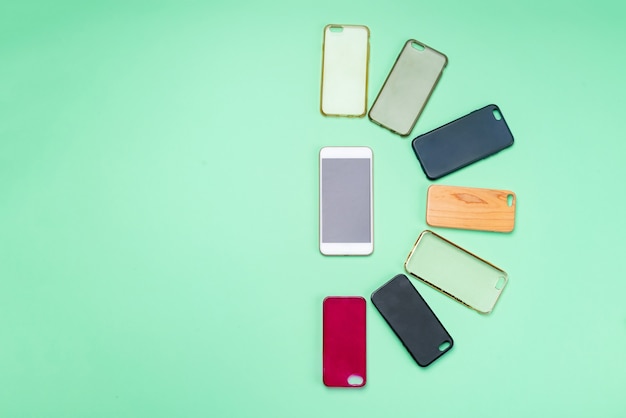 Escolha de capas traseiras de plástico multicoloridas para telefones celulares em fundo verde com um smartphone na lateral