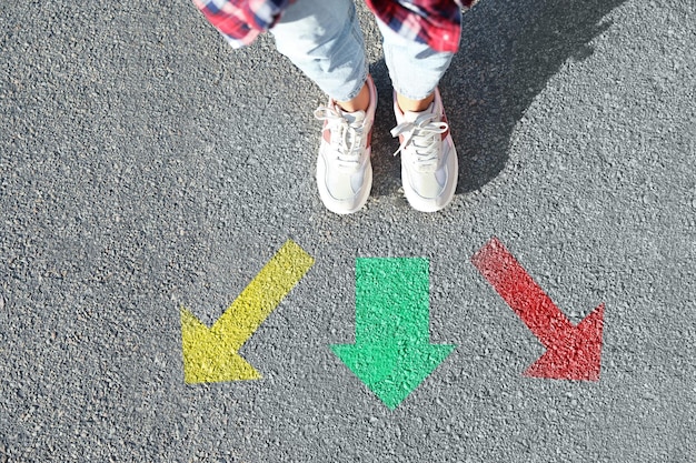 Escolha do caminho Mulher parada na frente de marcas desenhadas na estrada fechada Setas coloridas apontando em diferentes direções