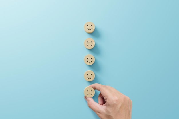 Foto escolha manualmente o bloco de cubo de madeira com sorriso de rosto de ícone em fundo azul claro os melhores serviços de negócios excelentes avaliando a experiência do cliente conceito de pesquisa de satisfação