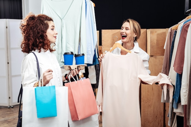 Escolhendo um novo vestido. Mãe atraente e elegante rindo enquanto escolhe um vestido novo com a filha