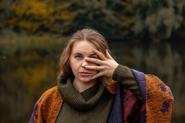 Esconde-esconde. a menina cobriu o rosto com as mãos. Retrato do close-up em um lago O conceito de dor feminina, tristeza, violência, depressão, solidão.