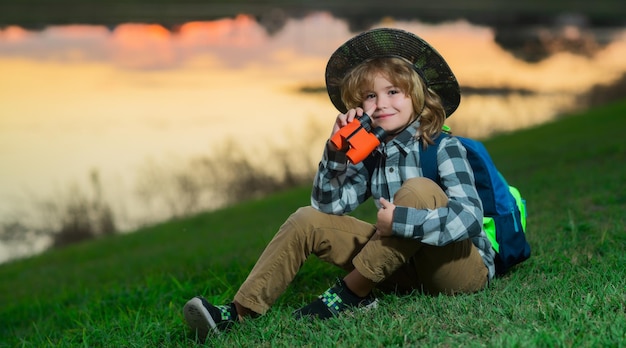 Escoteiro usando chapéu de explorador e mochila ao ar livre Explorador e aventura com binóculo