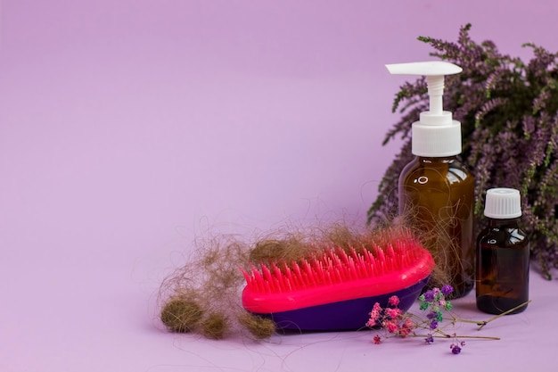 Escova de cabelo de garrafas de medicação e urze de ervas em fundo roxo Problema de perda de cabelo