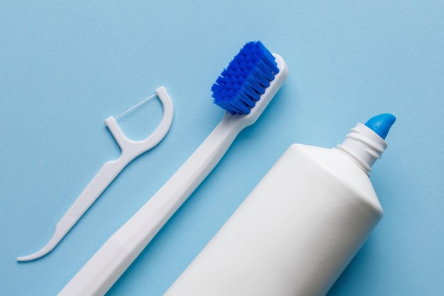 Escova de dentes branca com creme dental e fio dental em um fundo azul