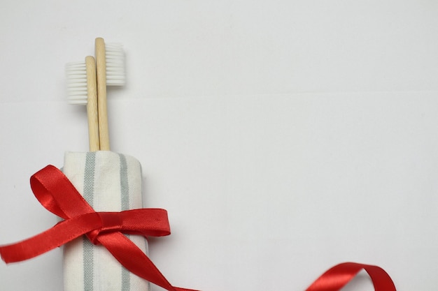Escova de dentes de bambu ecológica com toalha de banheiro e fita vermelha sobre fundo branco