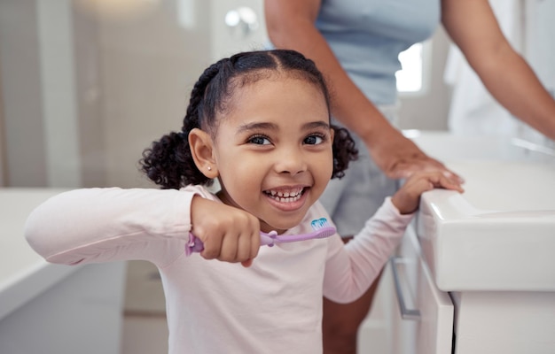 Escova de dentes e pasta de dentes para crianças com uma menina escovando os dentes no banheiro em casa para higiene ou cuidados dentários dentes e boca de saúde com uma criança bonita praticando bons hábitos orais