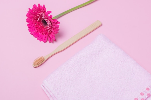 Escova de dentes ecológica de bambu e flor em fundo rosa