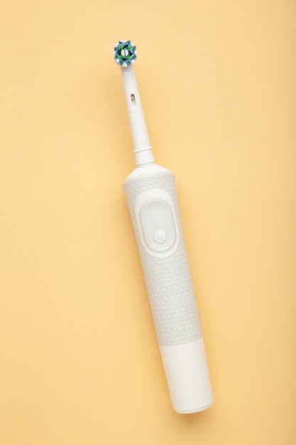 Escova de dentes elétrica moderna em fundo bege Ferramenta controlada para cuidados bucais diários