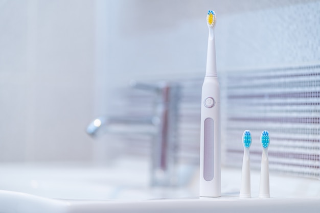 Escova de dentes elétrica ultra-sônica com bocais intercambiáveis no banheiro em casa. higiene bucal, saúde bucal e dentária, dentes saudáveis.