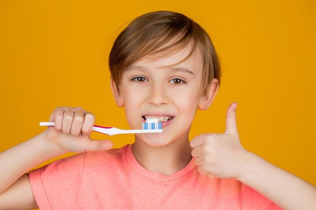 Escova de dentes para menino pasta de dente branca Criança alegre mostra escovas de dentes mostra um polegar para cima Garotinho limpando os dentes Higiene dental Criança feliz escovando os dentes Garoto escovando os dentes