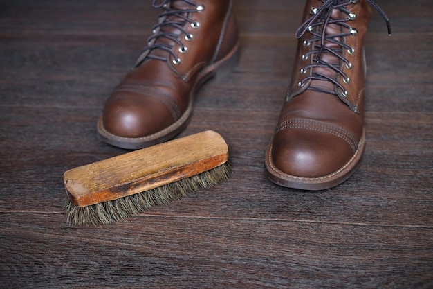 escova de sapato de madeira no piso de madeira ao lado de novas botas de couro