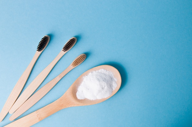 Escovas de dente de bambu e refrigerante em um fundo azul, espaço de cópia de vista superior, conceito de estilo de vida ecológico