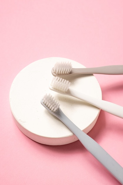 Escovas de dentes cinza e brancas sobre fundo rosa. Cuidando dos dentes, conceito dental. Foto plana lay, cópia espaço, vista superior.