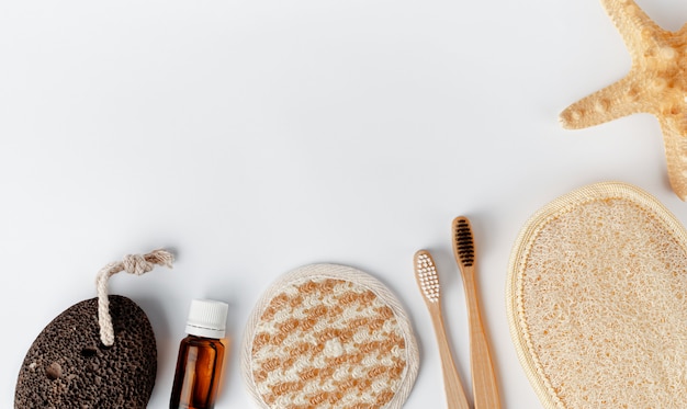 Escovas de dentes de bambu, esponjas de rosto e corpo, óleo essencial e pedra-pomes em branco