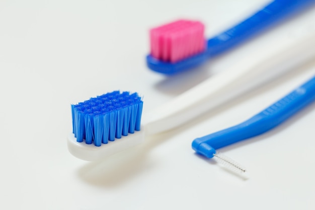 Escovas de dentes e escova interdental em fundo branco.