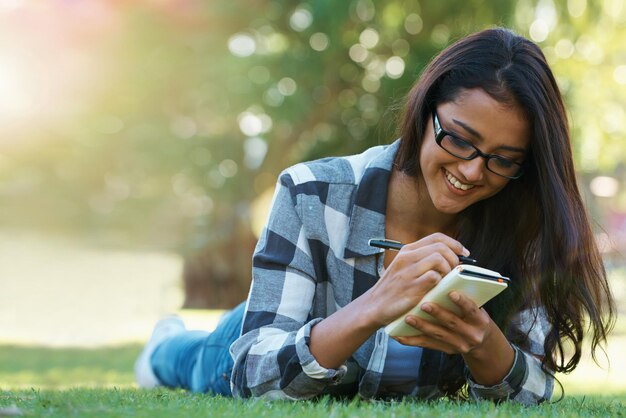 Foto escrever grama ou mulher feliz no parque com anotações para aprender informações de conhecimento ou educação diário de sorriso ou estudante na natureza para estudar ideia ou paz no gramado do campus da faculdade para relaxar