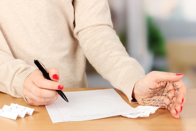 Escribe el examen en una mesa de madera en el fondo de la habitación