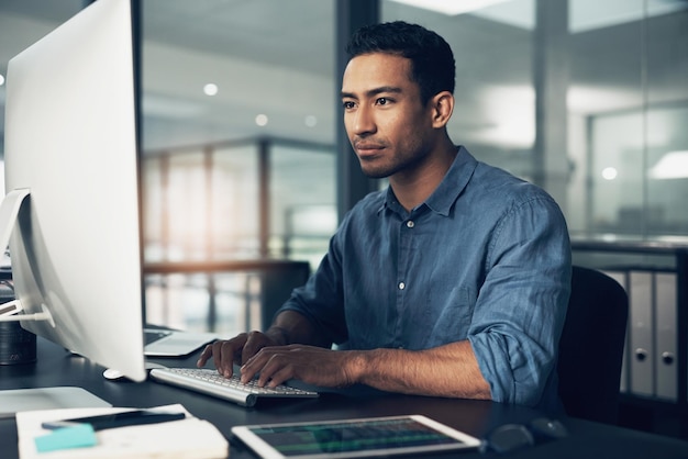 Escribiendo hombre y programador en la computadora en la oficina por la noche para la fecha límite Enfoque de TI e ingeniero codificador masculino o persona programando codificación y escritura desarrollo de software y tecnología de la información