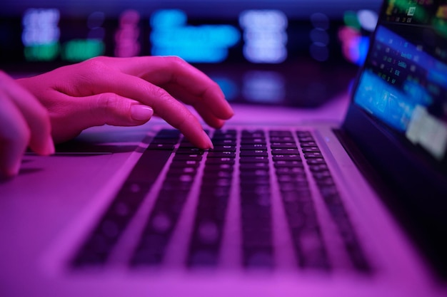 Escribiendo en el teclado de la computadora portátil en una habitación con poca luz