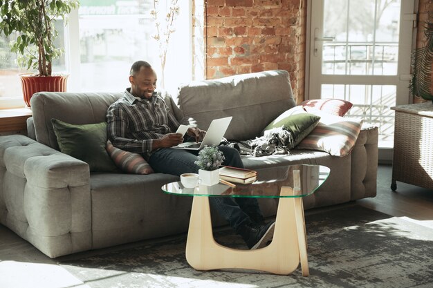 Escribiendo texto. Hombre, autónomo durante el trabajo en la oficina en casa mientras está en cuarentena. Hombre de negocios de sexo masculino joven que se queda en casa, uno mismo aislado. Usando gadgets. Trabajo remoto, prevención de la propagación del coronavirus.