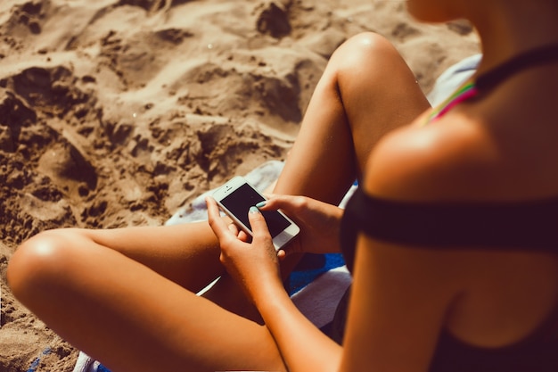 Escrita da menina em um móbil na praia
