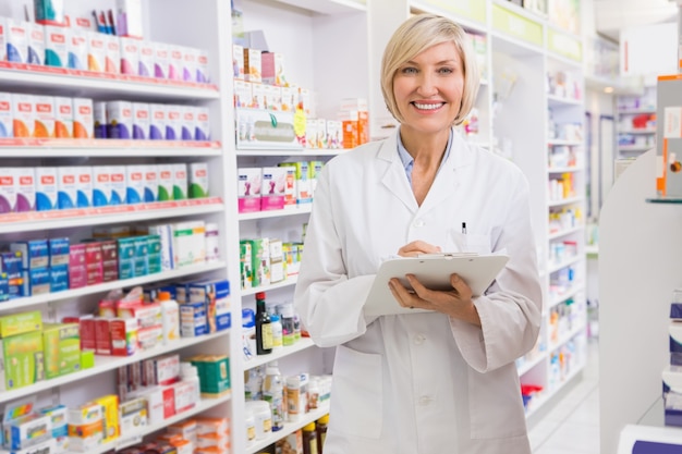 Escrita de farmacêutico sorridente na prancheta