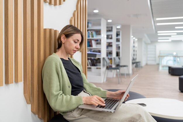 Escritora freelance de mulher focada trabalhando em laptop na biblioteca Freelancing após 40