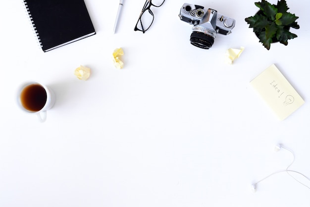 escritorio blanco liso con cámara vieja, cuaderno, gafas, pegajoso