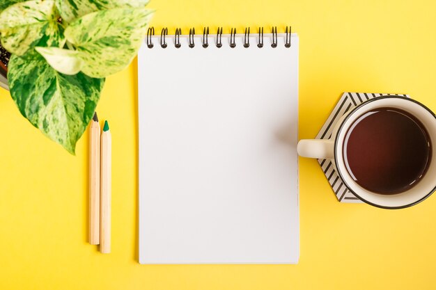 Escritorio con bloc de notas en blanco y taza de té