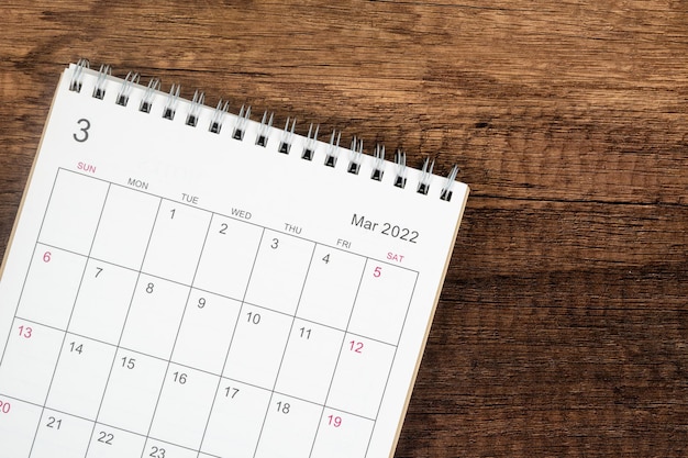 Escritorio de calendario 2022 en el mes de marzo, calendario de vista superior para que el organizador planifique sobre el fondo de la mesa de madera. Concepto de reunión de cita de planificación empresarial