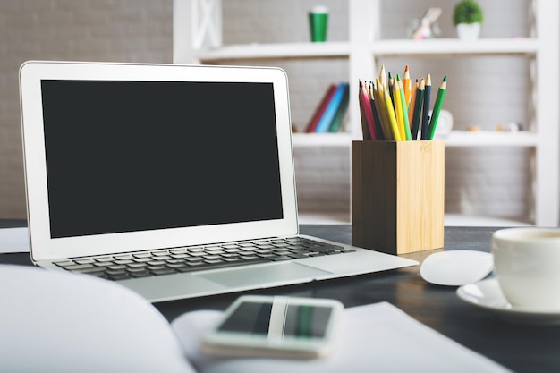 Escritorio creativo con pantalla de portátil en blanco