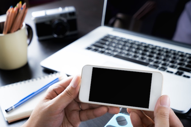 Foto escritório criativo está segurando uma tela do smartphone em branco para mock up