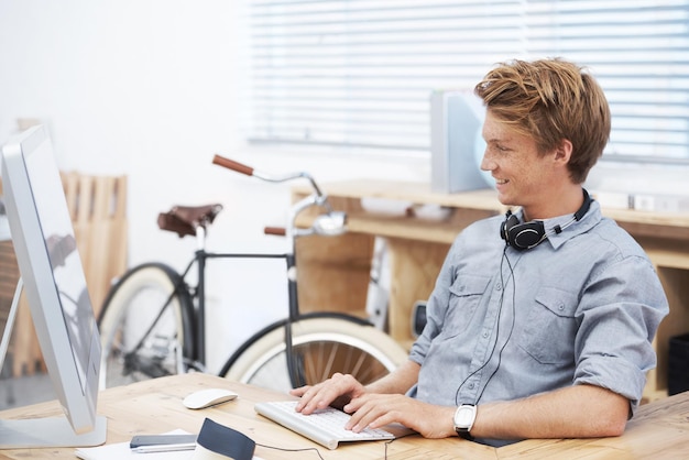 Escritório de inicialização do homem e digitando com computador sorridente e criatividade para postar no site de mídia social Jovem empresário empresário e especialista em seo na web com felicidade em pequenas empresas por computador