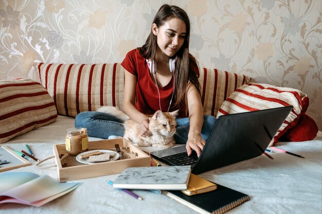 Escritório em casa espaço de trabalho trabalho em casa conceito jovem mulher com laptop e gato trabalhando no sofá