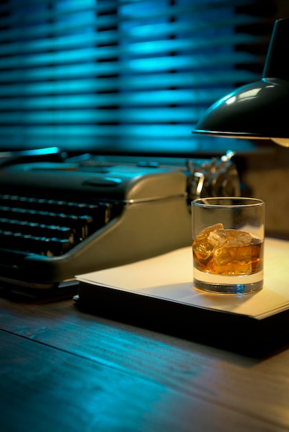 Escritorio de escritor vintage con máquina de escribir y un vaso de whisky