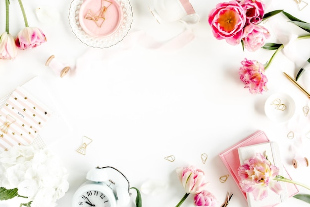 Escritorio de estilo rosa de blog de moda con accesorios flores de tulipán tijeras taza de café sobre fondo blanco