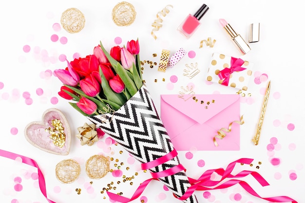 escritorio de estilo rosa y dorado con flores, tulipanes rosados, cosméticos y accesorios femeninos